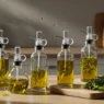 Top 5 glass olive oil sprayers for cooking displayed on a kitchen counter with fresh herbs – Dr Top List Amazon affiliate guide.